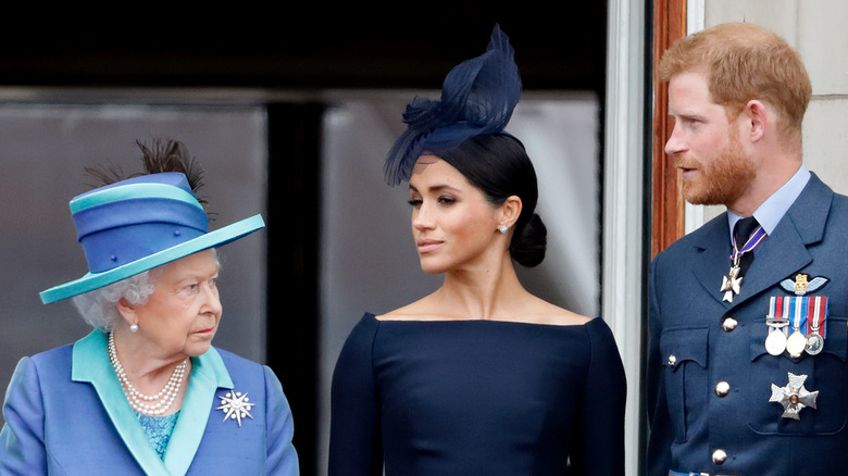 The queen stands next to Meghan Markle and Prince Harry