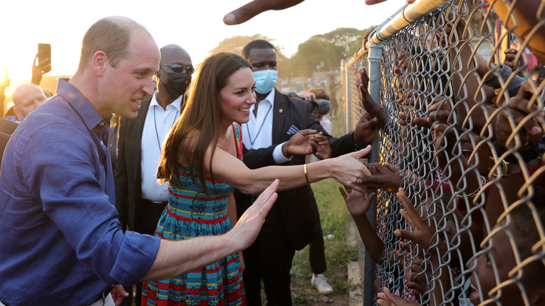 Prince William and Princess Catherine greeting children behind a fence