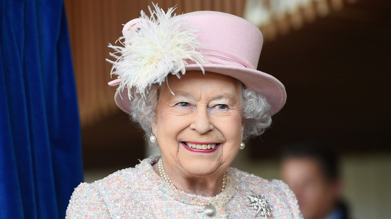 Queen Elizabeth in pink hat smiling