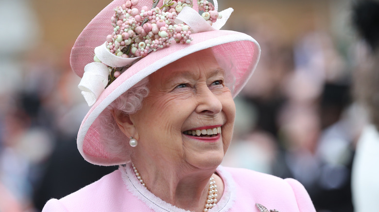 Queen Elizabeth wearing all pink, smiling to the public