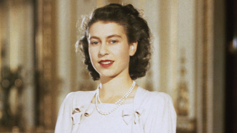 A young Queen Elizabeth II poses for a photo with curly brown hair