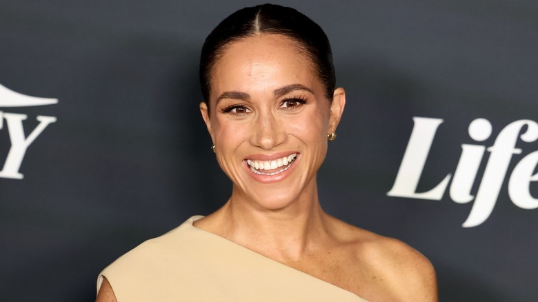 Closeup of Meghan Markle smiling on step-and-repeat