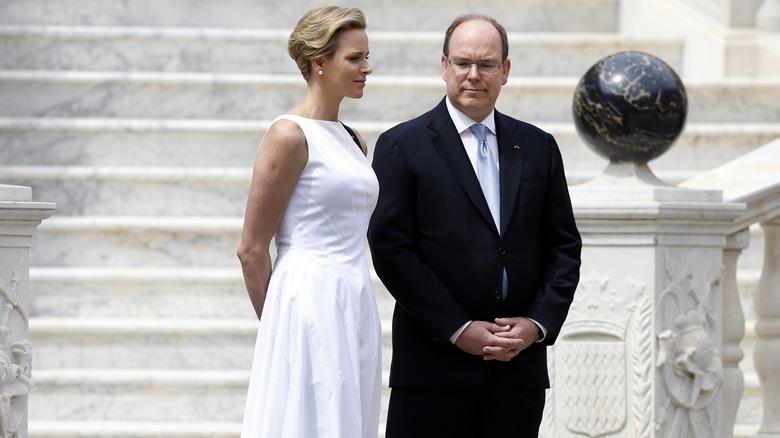 Princess Charlene and Prince Albert standing outside at the bottom of grand marble steps