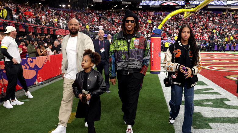 Jay-Z walking around football field with daughters Rumi and Blue Ivy