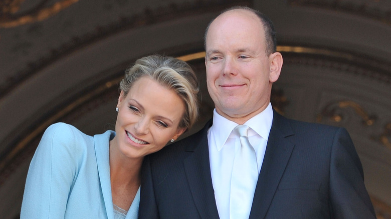 Princess Charlene smiling while leaning on Prince Albert's shoulder