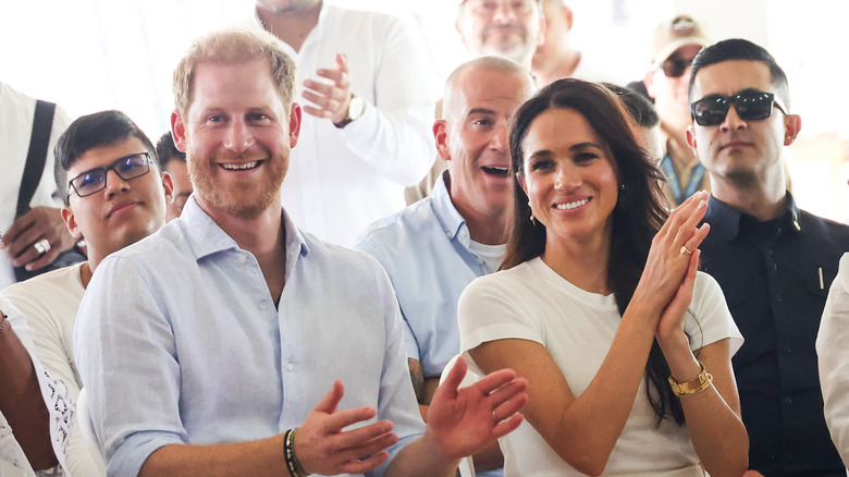 Meghan Markle and Prince Harry smiling and clapping