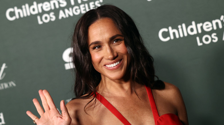 Meghan Markle smiling and waving on red carpet