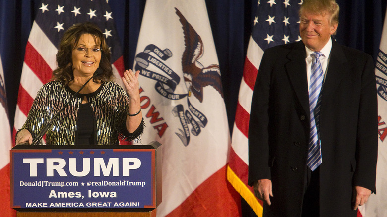 Donald Trump smiles as Sarah Palin speaks onstage