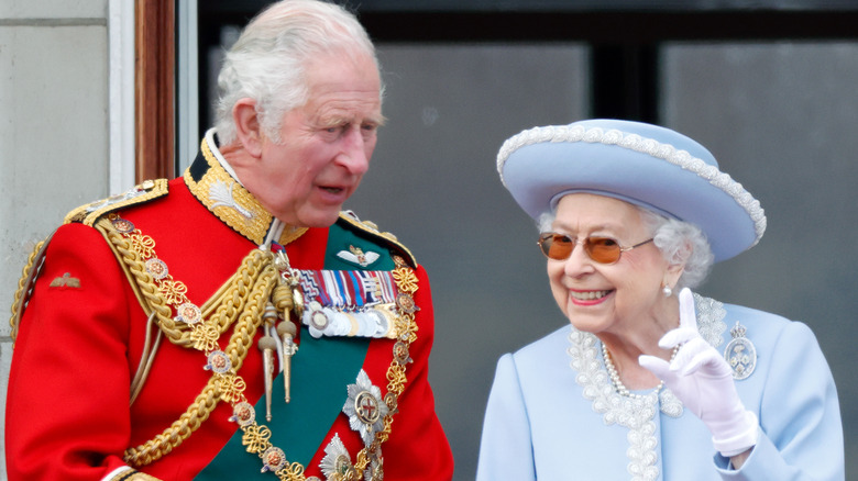 King Charles in green sash, speaking to Queen Elizabeth