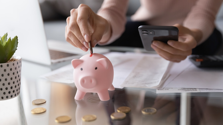 Person putting coins in a piggy bank