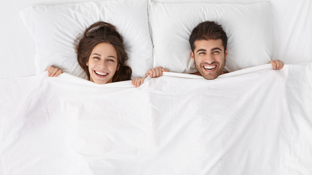 Happy married couple smiling in bed