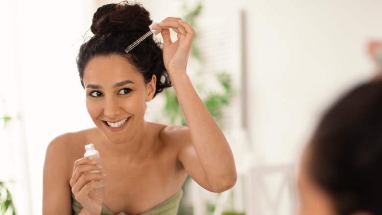 woman applying oil to scalp with dropper