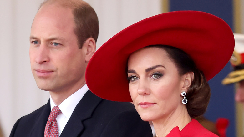 The Prince and Princess of Wales standing next to each other looking serious