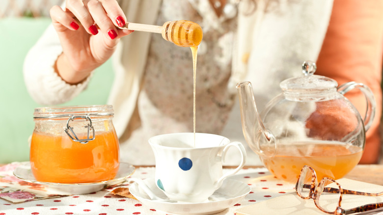 pouring natural remedy honey into tea