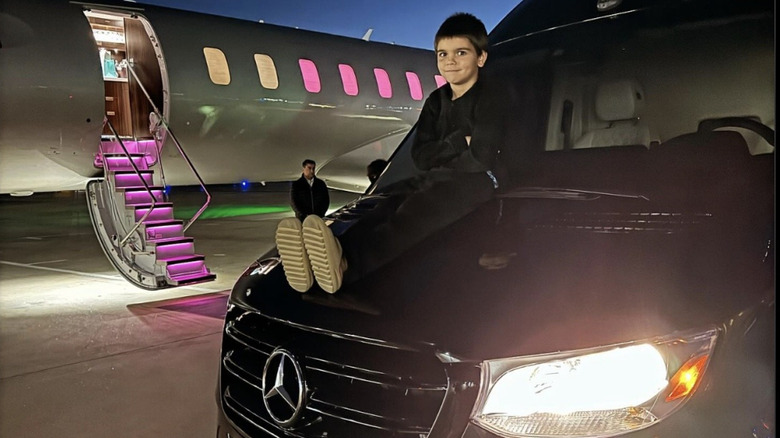 Reign Disick sitting atop a black Mercedes van