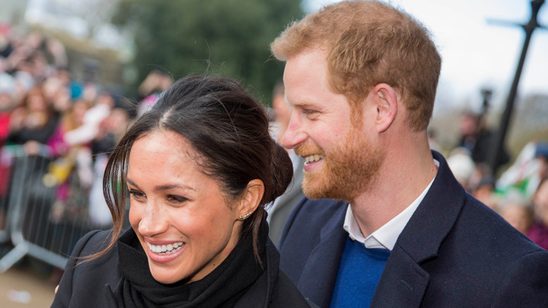 Prince Harry with arms on Meghan's shoulders