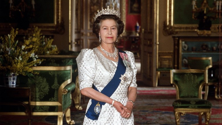 Queen Elizabeth posing in grand hall wearing white dress 