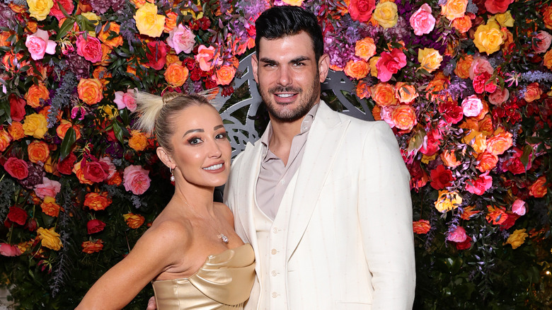 Mary Fitzgerald and Romain Bonnet posing by flower arch