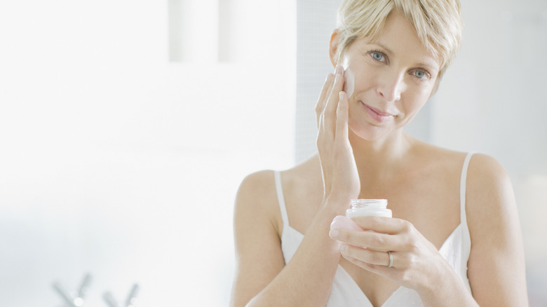 A woman applying face cream 