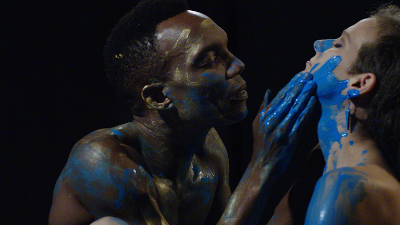 a man puts blue paint on a woman's face