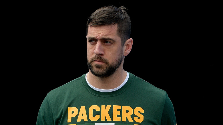 Aaron Rodgers looking pensive against a black background