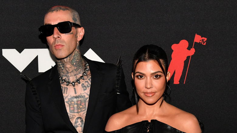 Kourtney Kardashian and Travis Barker posing at an event.