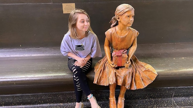 Shauna Rae sitting next to statue of little girl