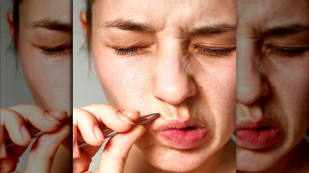 Woman plucking facial hair