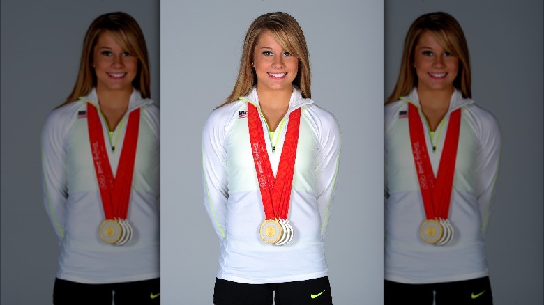 Shawn Johnson posing with Olympic medals