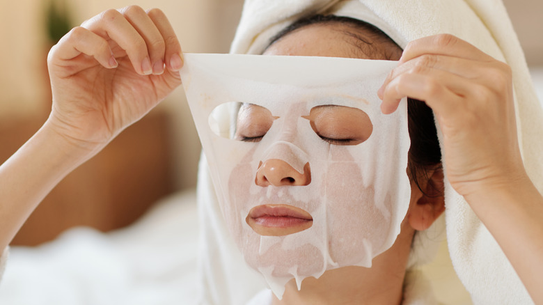 Woman putting on a sheet mask