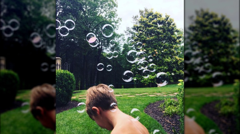 Sheryl Crow's young son playing amid bubbles outdoors