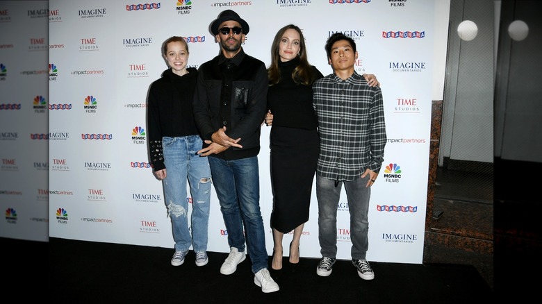 Angelina Jolie posing with artist JR and her kids