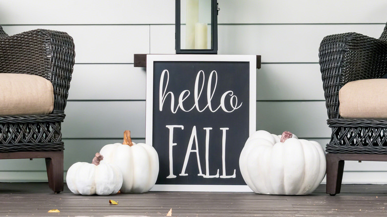 A sign reading Hello Fall with white pumpkins