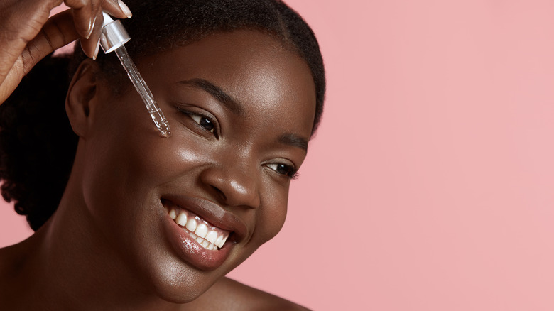 Woman applying facial serum to skin