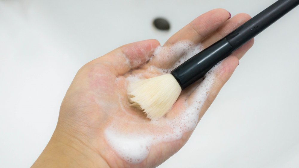 hand cleaning a makeup brush with soap