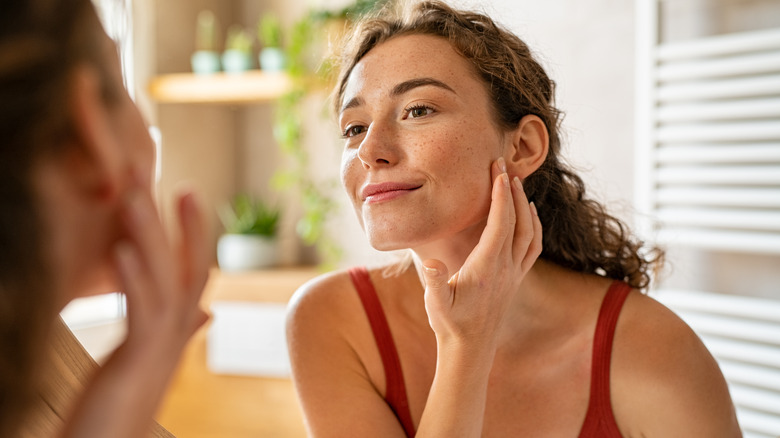 Woman looking at her face in the mirror