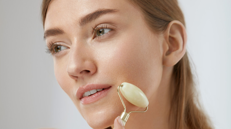 Young woman using a jade roller on her face