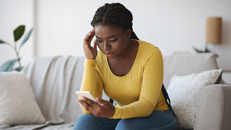 Woman holding phone looking troubled