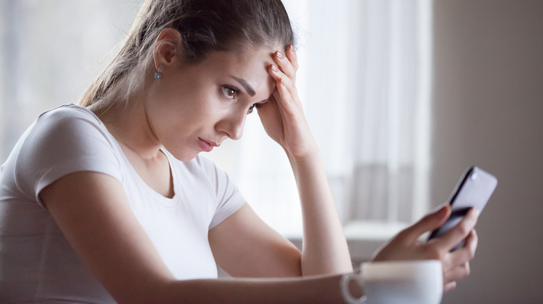 Woman looking at phone concerned