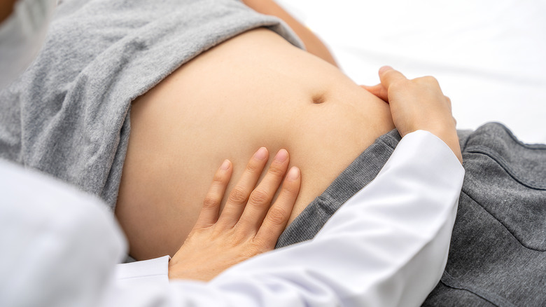 Woman getting her abdomen examined by a doctor