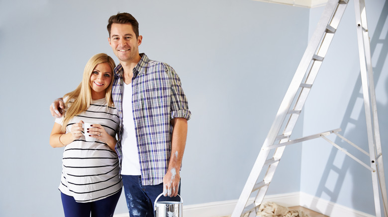 pregnant couple decorating the nursery