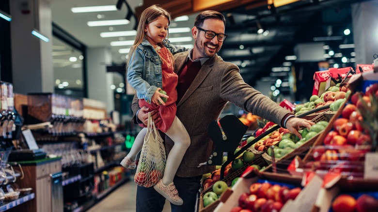 Father and daughter select apples at store 