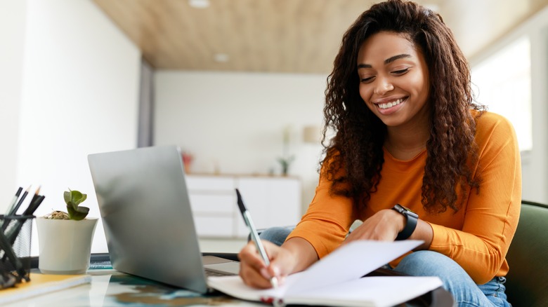 Woman joyfully smiling as she writes