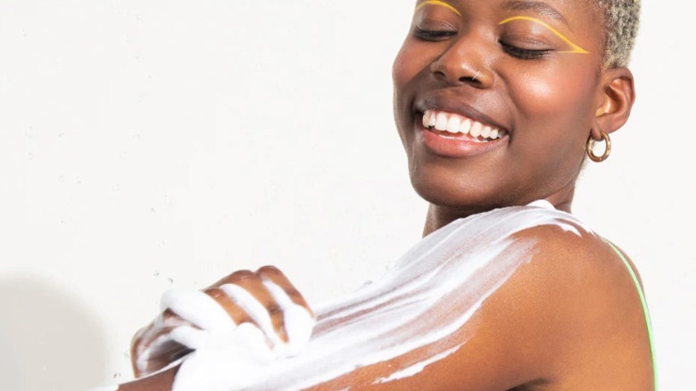 Smiling woman lathering shower foam