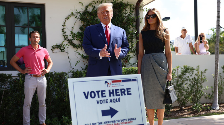 Melania and Donald Trump stand in front of polling station