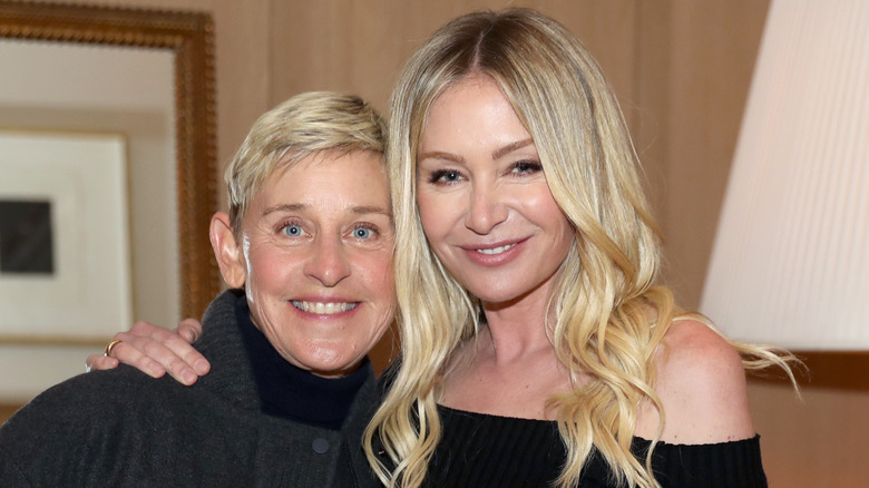 Smiling Ellen DeGeneres and Portia de Rossi posing for photo together