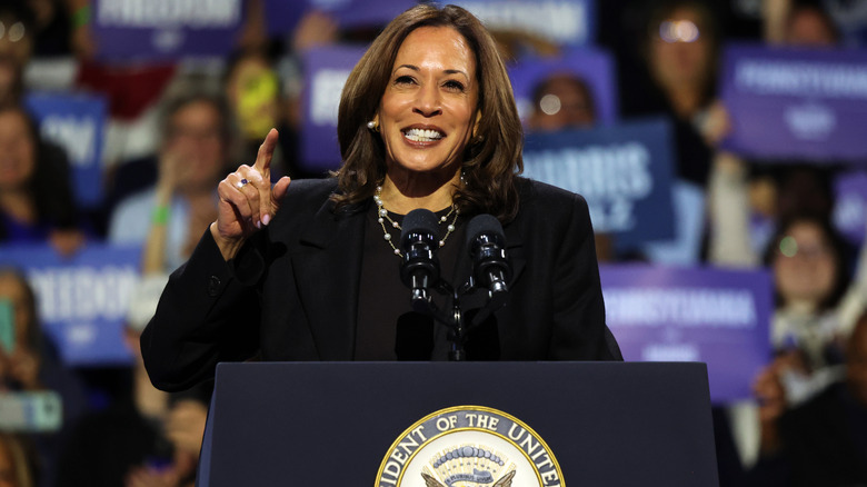 Kamala Harris speaking in a dark suit and pearl necklace