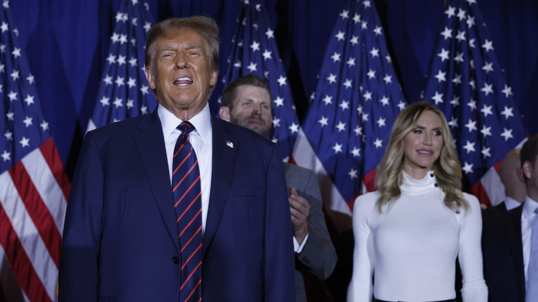 Lara Trump claps while standing behind Donald Trump who is speaking