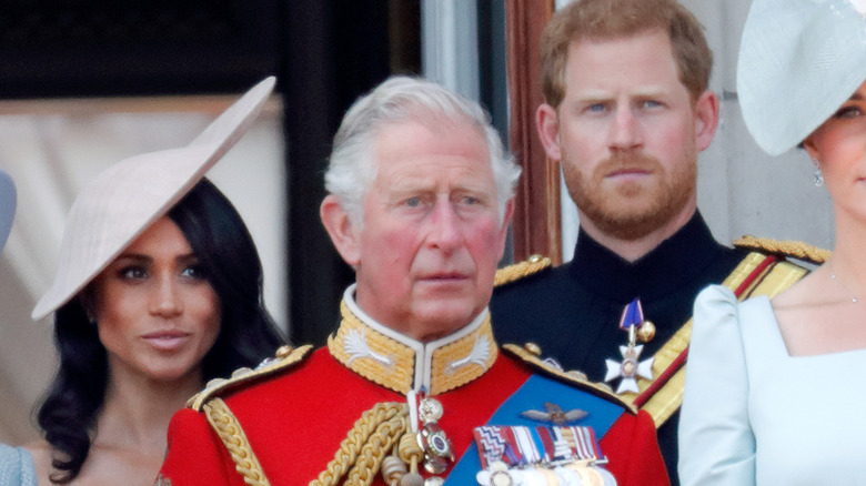 Prince Harry standing behind King Charles III