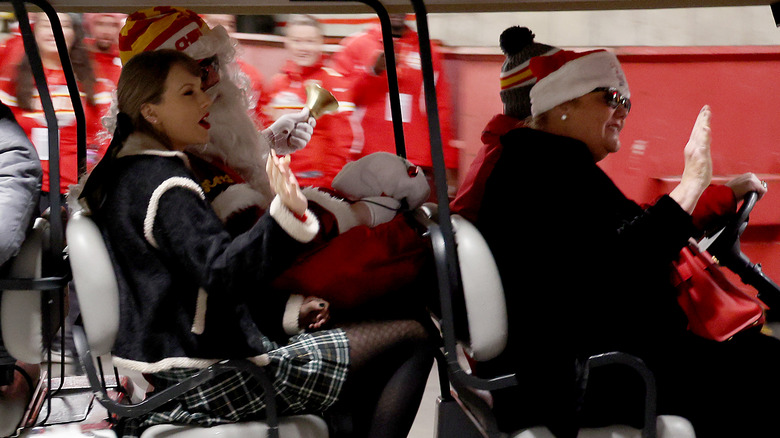 Taylor Swift, Austin Swift, and Andrea Swift in a golf cart at Arrowhead Stadium